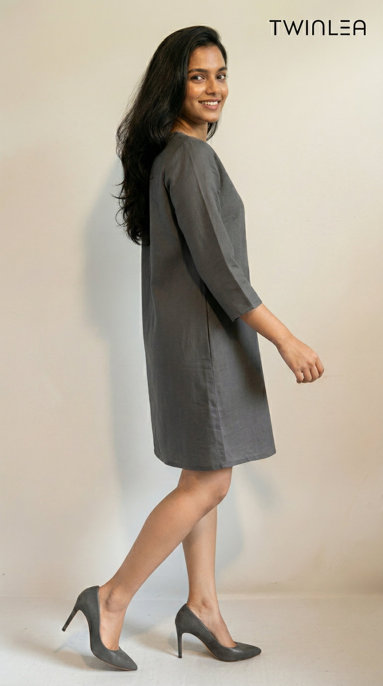 Model wearing a gray dress with a plain background, featuring the brand 'TWINLEA'.